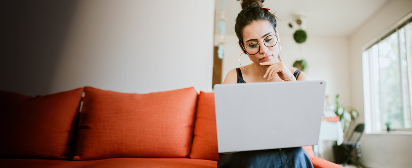 woman sitting on cough looking at laptop