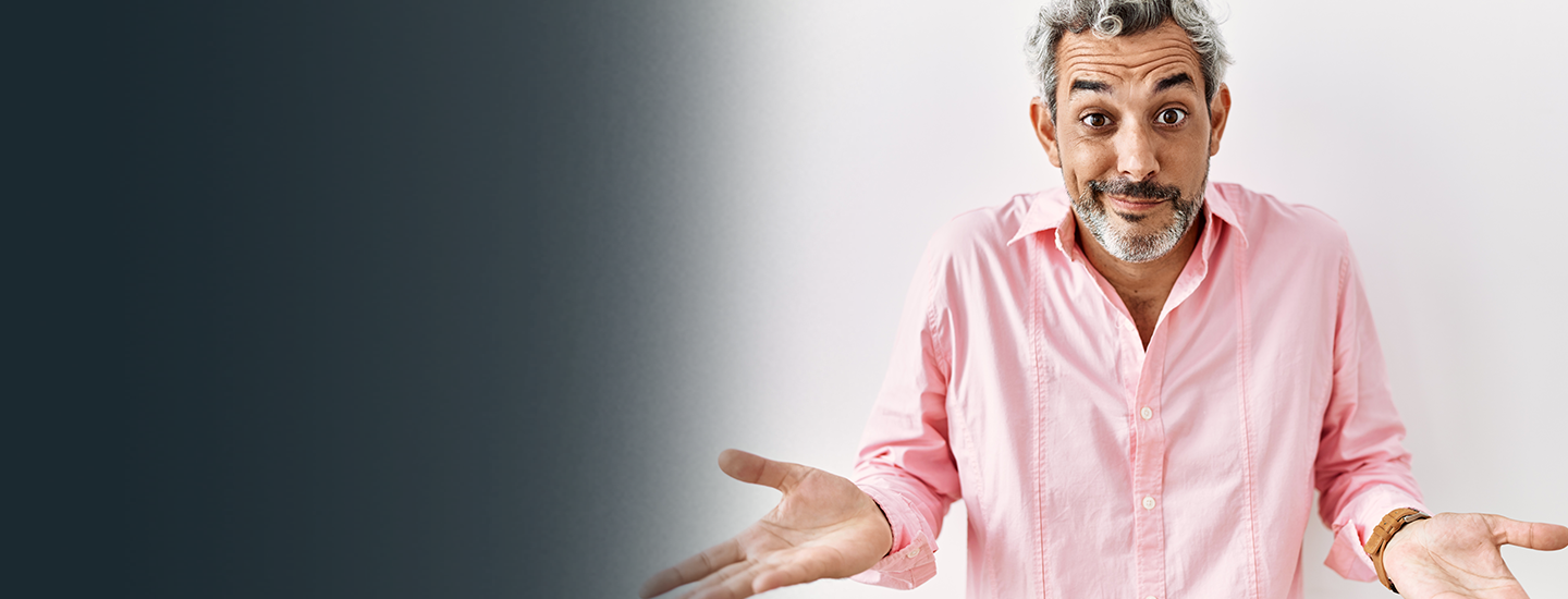 man in pink shirt with gray hair shrugging