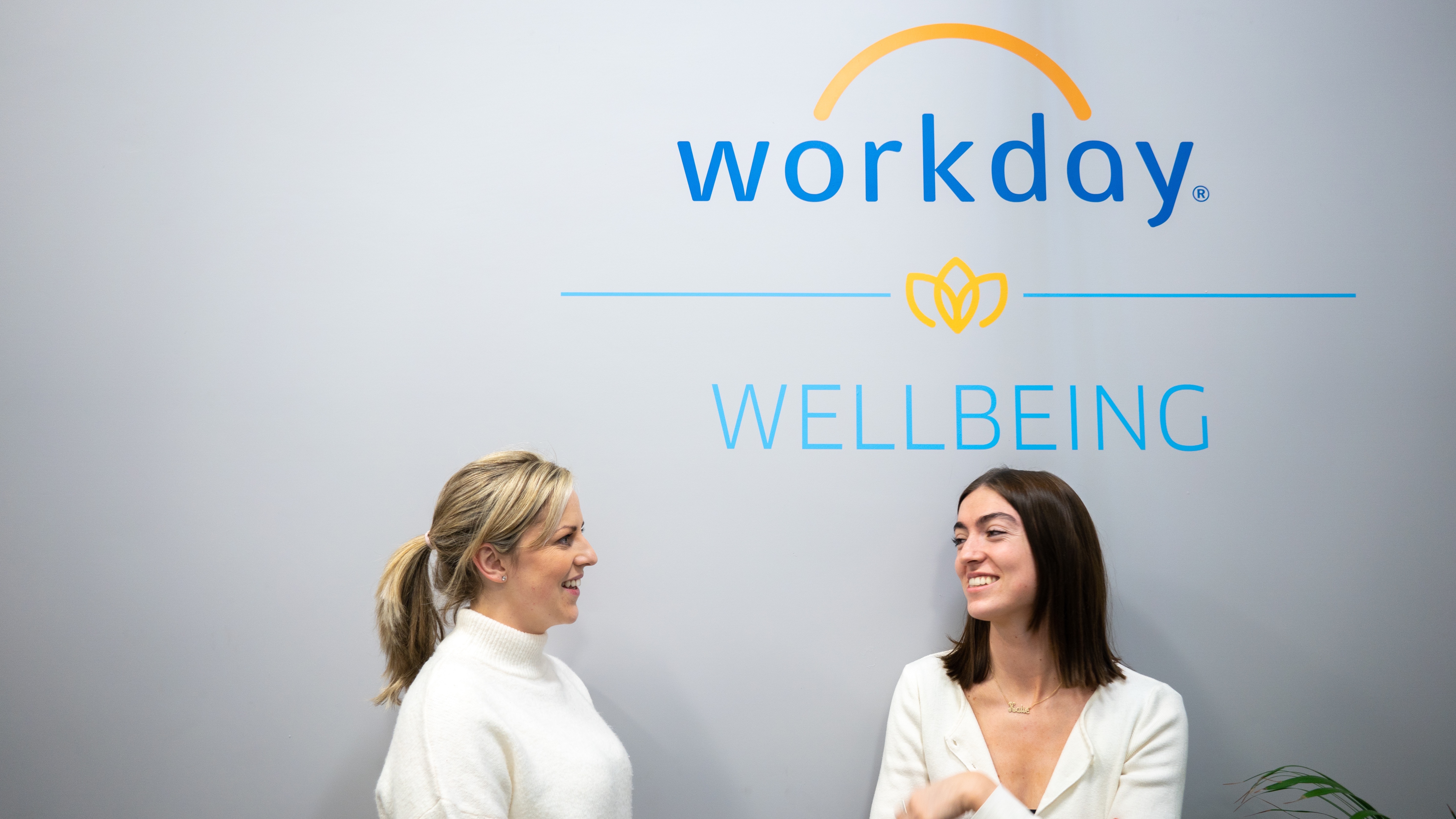 workday employees talking near wall that says wellness