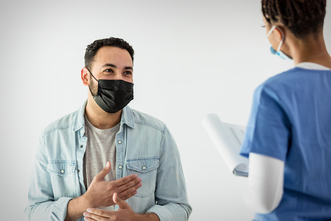 man in mask talking to medical professional in mask